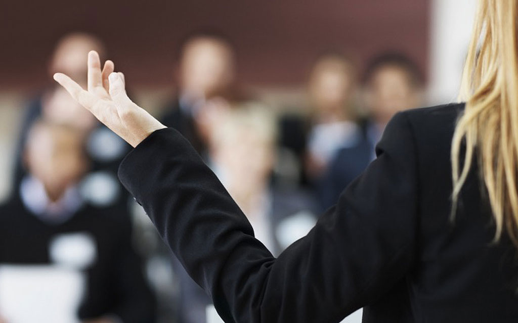 Woman holding up he hand in front of blurred people