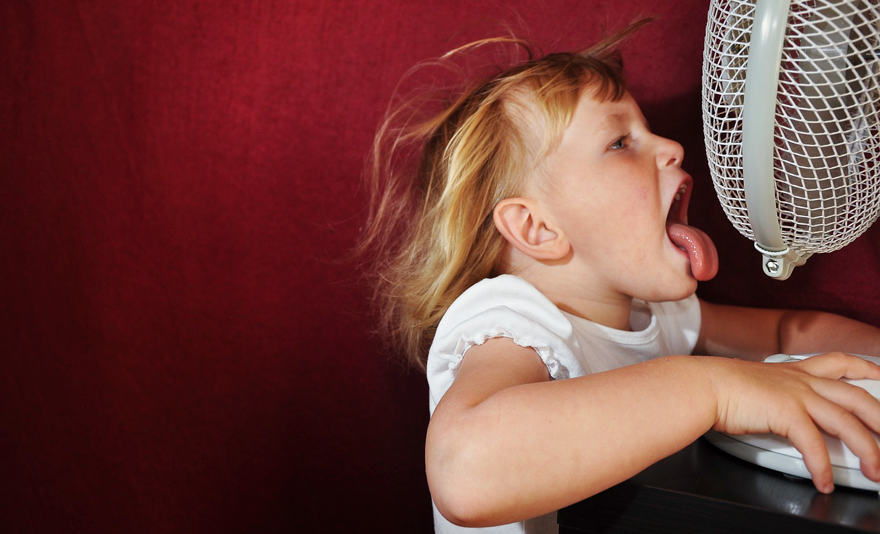 Girl using a desk fan to stay cool during the heat